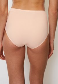 Perizoma a vita alta color nude realizzato in materiale liscio ed elastico. Presenta un design senza cuciture e aperture per le gambe sottili per comfort e vestibilità.