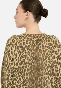 Maglione lavorato a maglia con motivo leopardato in tonalità beige e marrone, caratterizzato da un collo rotondo e un piccolo etichetta del marchio sul retro.