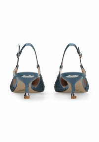 Escarpins slingback bleus avec petits clous, talons aiguilles étroits et brides réglables à la cheville, vus de dos sur fond blanc.