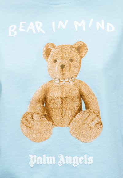 Ανοιχτό μπλε φούτερ με μεγάλο, λεπτομερή εκτυπωμένο σχέδιο ενός καφέ αρκουδάκι με περιλαίμιο. Κείμενο «BEAR IN MIND» πάνω και «Palm Angels» κάτω σε άσπρο χρώμα.