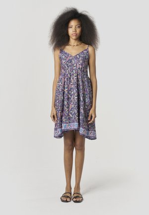 Vestido morado con estampado de cachemira, falda acampanada, tirantes delgados y un dobladillo decorativo. Combinado con sandalias planas negras.