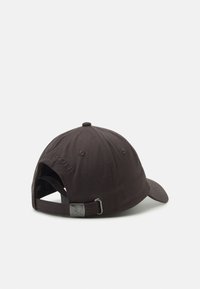 Casquette de baseball marron foncé avec une visière courbée, tissu texturé, sangle ajustable à l'arrière et un petit accent en métal.