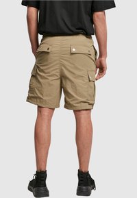Khaki cargo-shorts, jotka on valmistettu kevyestä kankaasta, sisältävät useita sivutaskuja, rento istuvuus ja takana joustava vyötärönauha.