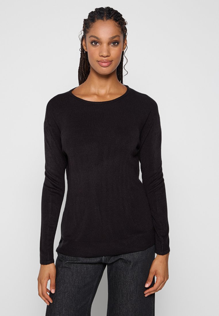 Schwarzer Langarmpullover mit rundem Halsausschnitt, geripptem Design und lockerer Passform. Mit dunklen Jeans für einen lässigen Look getragen.
