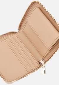 Portefeuille beige zippé avec plusieurs emplacements pour cartes, texture en cuir lisse, quincaillerie de fermeture éclair en ton doré et une petite étiquette de marque attachée.
