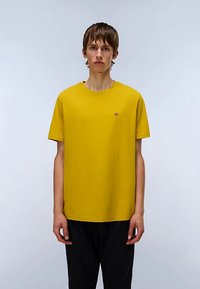T-shirt jaune à manches courtes en coton doux, avec un petit logo sur la poitrine gauche. Coupe décontractée et texture lisse.