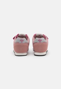 Des baskets en suede rose avec des accents gris, bout rond, fermeture à lacets et col rembourré présentent un logo au talon et une semelle texturée.