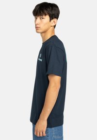 Marineblaue Baumwoll-T-Shirt mit kurzen Ärmeln, rundem Ausschnitt und Logo auf der Vorderseite. Enganliegende Form, glatte Textur und minimalistisches Design.