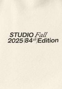 Tessuto bianco con testo nero: "STUDIO Edizione Autunno 2025 (84°)". Il testo è in grassetto con una leggera texture, posto su uno sfondo liscio.