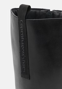 Černá kožená bota s měkkou texturou, zaobleným vrchem a postranním poutkem s embosovaným nápisem "Copenhagen shoes" v šedé barvě.