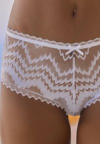 Culotte en dentelle blanche avec un motif festonné, un détail en forme de nœud délicat au centre devant, et une texture transparente, offrant un aspect doux.