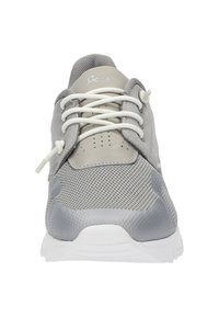 Grauer Sportschuh mit einem Obermaterial aus Netzgewebe und Lederakzenten, runden Schnürsenkeln und einer strukturierten Sohle. Weiße Zwischensohle mit Belüftungslöchern.