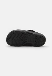 Black rubber shoe sole with textured tread pattern, featuring a molded design and circular logo, designed for grip and durability.