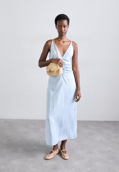 Light blue, sleeveless dress with a V-neck and gathered side detail. Paired with a textured cream crossbody bag and beige flats.