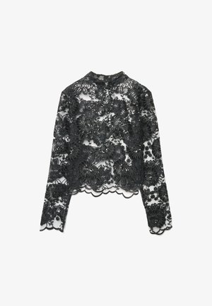 Top nero in pizzo a maniche lunghe con motivi floreali e orlo smerlato. Presenta dettagli intricati con perline su tessuto trasparente.
