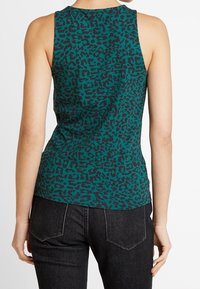 Bezruční tyrkysový top s černým leopardím potiskem, vyrobený z měkké látky. Zadní strana má hladký povrch s kulatým výstřihem.