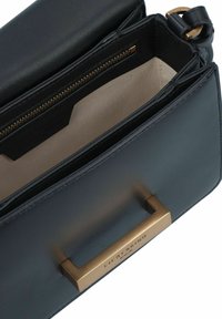Borsa a tracolla in pelle nera con dettagli in hardware bronzato. Presenta un scomparto con zip e una fodera interna liscia.