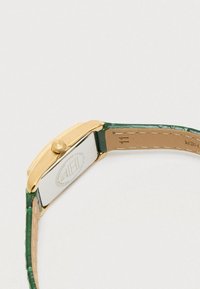 Gold-tone watch with a rectangular case, green faux crocodile leather strap, and a beige leather underside. Visible crown detail on the side.