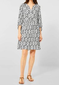 Robe à motifs noir et blanc, longueur genou, avec un décolleté en V et des manches trois-quarts. Tissu léger avec un détail de taille froncée.