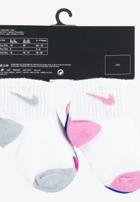 Fehér bokazokni bordázott mintával, rózsaszín és szürke Nike logóval. Színes díszítések a saroknál és a lábujjnál rózsaszín, kék és zöld színekben.