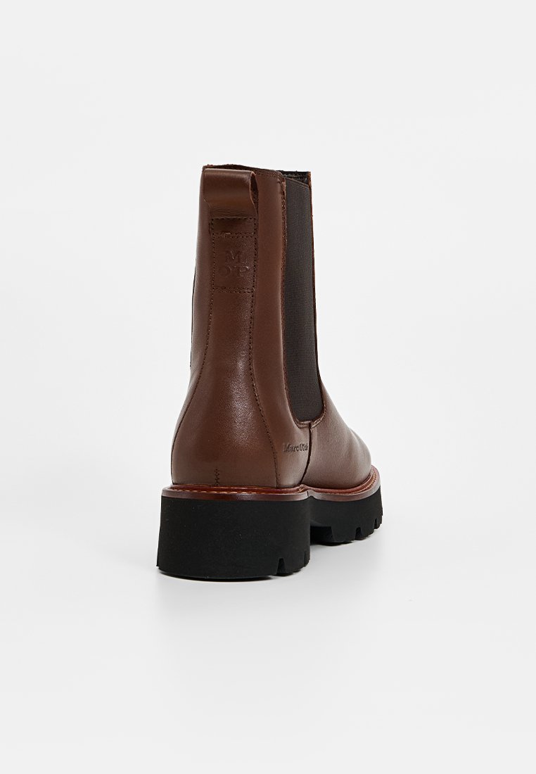 Braune Leder-Stiefeletten mit elastischen Seitenpaneelen, abgerundeter Zehenpartie, dicker schwarzer Sohle und kontrastierenden braunen Akzenten an Ferse und Sohle.