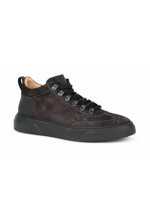 Black suede sneaker with thick rubber sole, metal eyelets, and black laces, shown from a side angle on a white background.