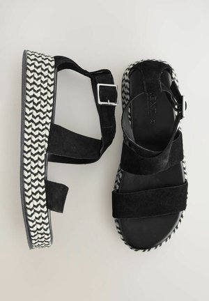 Czarne zamszowe sandały na platformie z plecionym wzorem houndstooth na podeszwie, z regulowanymi paskami na kostkę i płaskim obcasem.