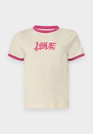 Krémové tričko s ružovým rebrovaným golierom a rukávmi. Na prednej strane je výrazná ružová grafika s textom "LOVE OF THE UNKNOWN".