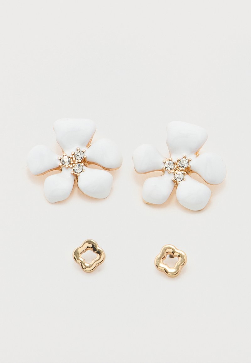 Ζεύγος σκουλαρικιών σε χρυσό τόνο με λευκά σμάλτα σε σχήμα πενταπέταλων λουλουδιών και τρεις μικρές διάφανες στρας στο κέντρο, συνοδευόμενα από καρφίτσες σε χρυσό τόνο με σχήμα λουλουδιού.