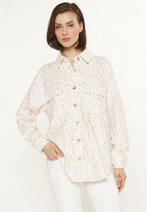 Knap-oppet skjorte i cremefarvet med et beige leopardprint. Har krave, lange ærmer og to brystlommer. Glat stofstruktur.