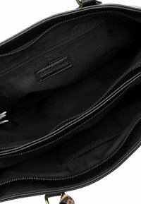 Black leather handbag interior with two compartments, one zippered pocket, and a brand label. Smooth texture; minimalistic design.