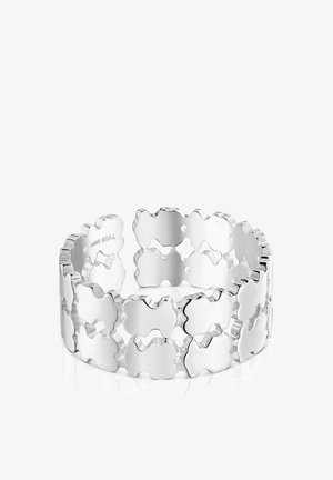 Brazalete de plata con un patrón enlazado de formas con bordes ondulados y recortes. Acabado liso y brillante con textura pulida.