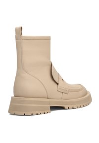Beige nahkasaappaat nilkkamittaisella varrella, pyöreällä kärjellä, sivuhihnalla ja paksulla pohjalla. Tasainen pintatunti hienovaraisilla ompeluaksentteilla.