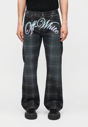 Άνδρας που φοράει μαύρο και γκρι καρό τζιν με φαρδιά πόδια και το "Off-White" γραμμένο μπροστά με γράμματα σε ανάγλυφη διαβάθμιση.