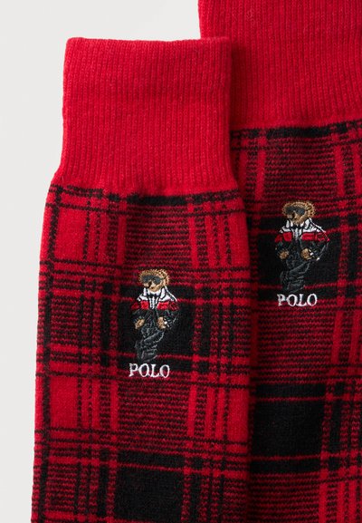 Chaussettes à carreaux rouges et noires avec un ours brodé portant une tenue sportive au-dessus du mot Polo.
