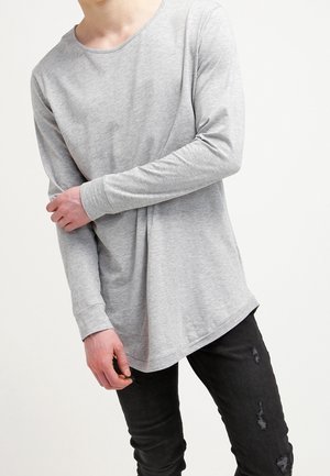 T-shirt gris à manches longues avec un col rond et une coupe décontractée, fabriqué en tissu doux. Assorti à un jean noir déchiré.