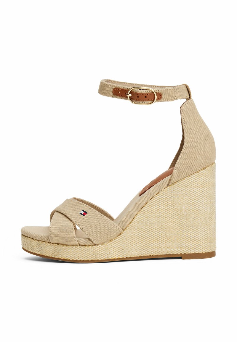 Sandales compensées beiges avec des brides en toile, croisées sur le devant, une sangle à la cheville avec boucle, et un talon compensé tressé texturé.