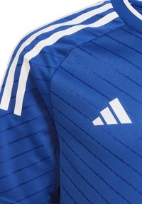 Maglia atletica blu realizzata in tessuto testurizzato con strisce verticali bianche e logo adidas in basso a destra.