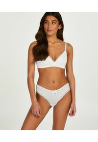 White lingerie set featuring a ribbed bralette with lace trim and bow, paired with matching briefs adorned with lace edges and a front bow.