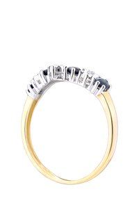 Zelta un sudraba gredzens ar izliekumu dizainu, kas dekorēts ar melniem dārgakmeņiem un caurspīdīgiem akcentu akmeņiem, ierāmēts mūsdienīgā un eleganta izskatā.