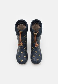 Une paire de bottes imperméables bleu marine avec un motif de fleurs jaunes, des fermetures à cordon brun et un intérieur en fourrure brune.