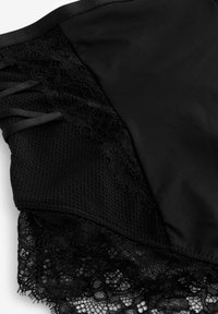 Zwarte lingerie met kantdetail, meshpanelen en satijnen stof. Inclusief decoratieve kantafwerking en lintaccenten aan de zijkant.