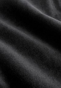 Schwarzer Stoff mit einer weichen, glatten Textur, der subtile Wellen und unterschiedliche Grautöne auf der Oberfläche zeigt.