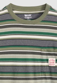 Camiseta a rayas verde y gris con cuello redondo, que presenta un pequeño bolsillo y una etiqueta roja en el borde del bolsillo. Material suave de mezcla de algodón.