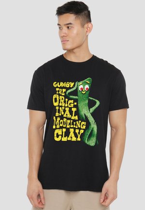 Black t-shirt featuring a green Gumby character with red eyes and a smile, accompanied by bold yellow text reading "Gumby The Original Modeling Clay."