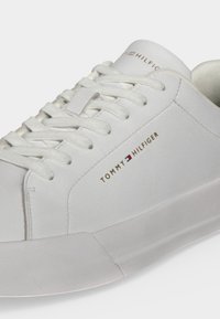 Λευκό sneaker χαμηλού τύπου με λευκά κορδόνια, υφή στη σόλα και λογότυπο Tommy Hilfiger στο πλάι και στη γλώσσα.