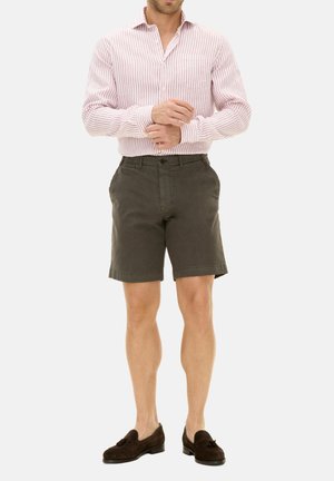 Stripet rød- og hvidternet skjorte, mørkegrønne shorts og brune loafers. Skjorten har lange ærmer og en brystlomme. Shortsene er knælange.