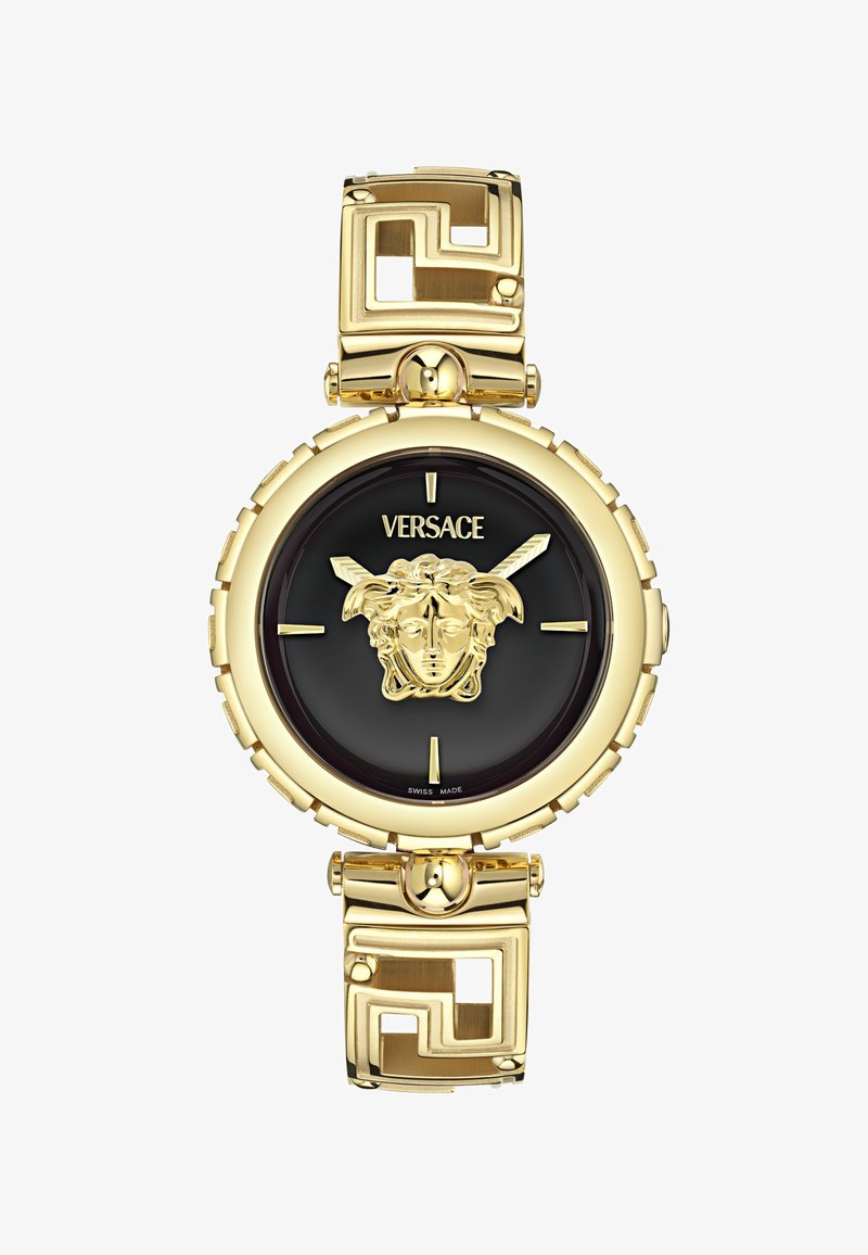 Kuldtoonine kell musta sihiku ja lõvikujutisega, millel on rihmal geomeetrilised lingid. Šveitsi valmistatud, ümar korpus.