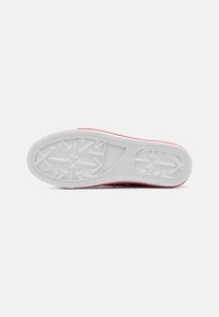 Suola di sneaker rossa e bianca con una superficie in gomma testurizzata caratterizzata da un motivo geometrico e un bordo rosso liscio.
