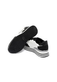 Zwart-witte sneakers met een gladde synthetische bovenkant, een gestructureerde zwarte hiel en een gestreepte zwart-witte zool. Bevat rubberen loopvlak voor grip.